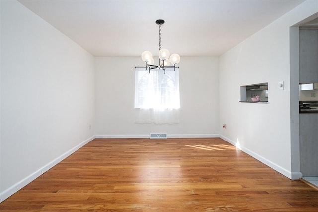 unfurnished dining area with visible vents, baseboards, an inviting chandelier, and light wood-style flooring