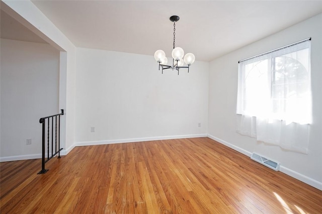 empty room featuring visible vents, baseboards, light wood-style floors, and a notable chandelier