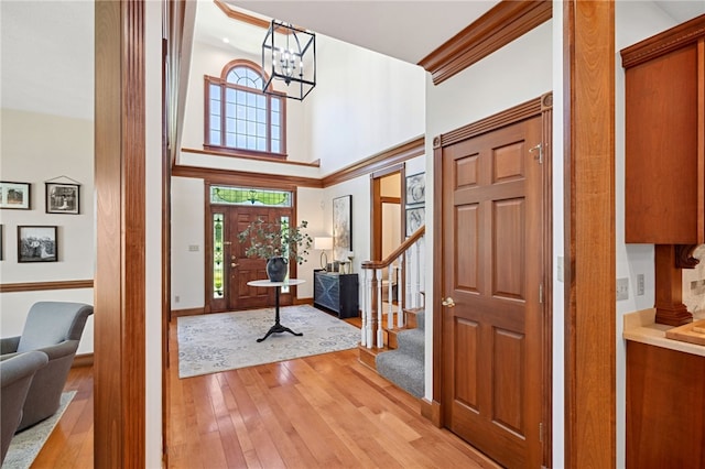 entryway with a notable chandelier, a towering ceiling, and light wood-type flooring