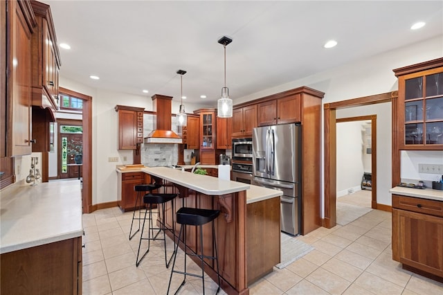 kitchen with decorative light fixtures, a kitchen island, backsplash, appliances with stainless steel finishes, and light tile floors