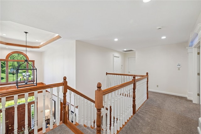 hallway with a tray ceiling and carpet