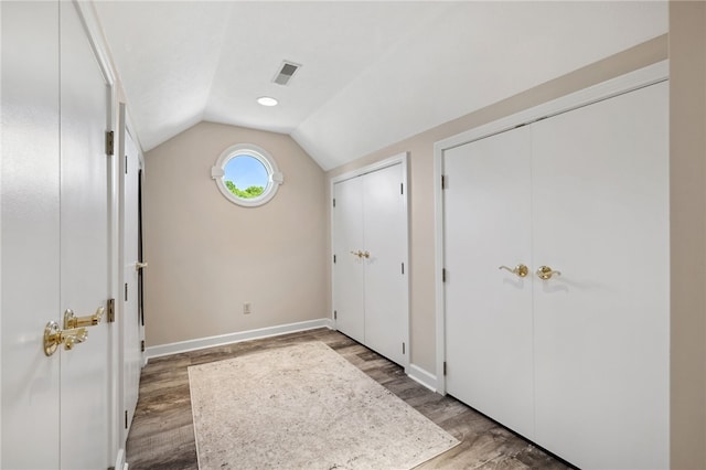 unfurnished bedroom featuring multiple closets, hardwood / wood-style flooring, and lofted ceiling