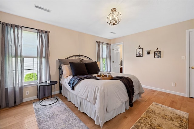 bedroom with a notable chandelier and light wood-type flooring