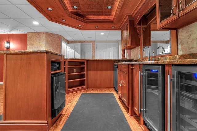 kitchen featuring beverage cooler, a tray ceiling, light hardwood / wood-style floors, and stone counters