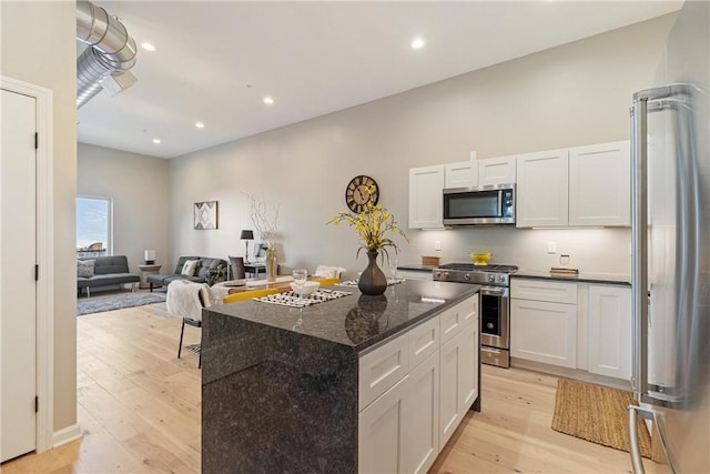 kitchen featuring stainless steel appliances, white cabinetry, a kitchen island, and light hardwood / wood-style floors