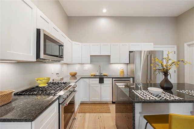 kitchen with appliances with stainless steel finishes, dark stone counters, and white cabinets