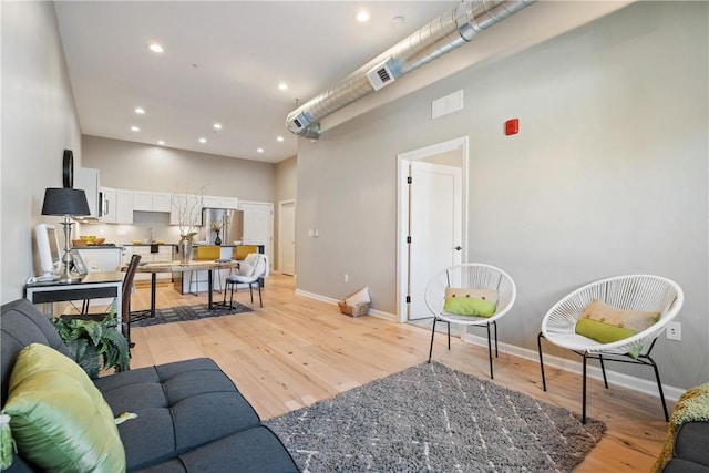 living room featuring a towering ceiling and light hardwood / wood-style floors