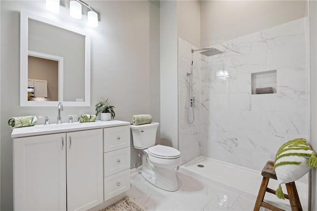 bathroom featuring a tile shower, vanity, and toilet