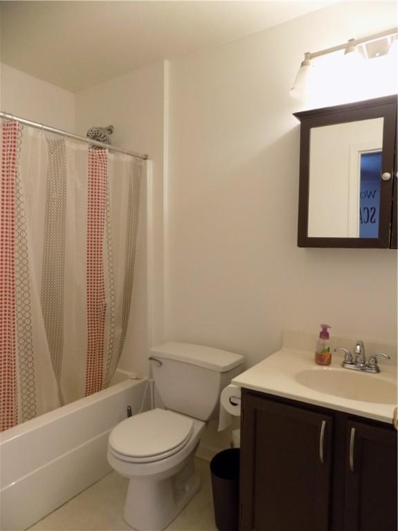 full bathroom featuring toilet, tile patterned flooring, shower / tub combo with curtain, and vanity