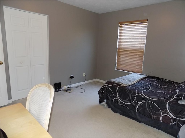 carpeted bedroom featuring a closet and baseboards