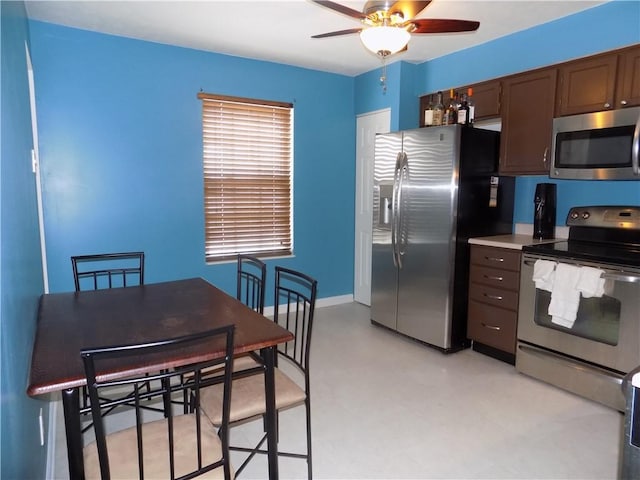 kitchen with dark brown cabinetry, baseboards, a ceiling fan, stainless steel appliances, and light countertops