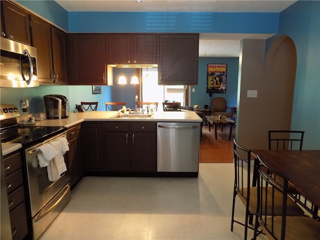 kitchen featuring stainless steel appliances, dark brown cabinets, sink, and kitchen peninsula