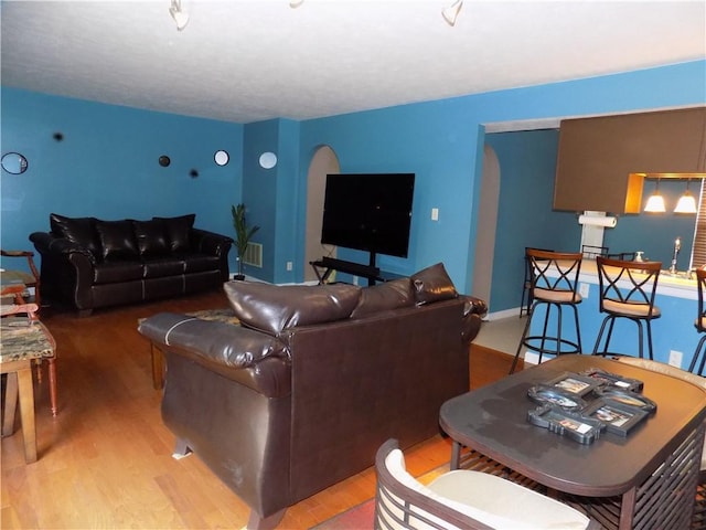 living area featuring baseboards, visible vents, arched walkways, and wood finished floors