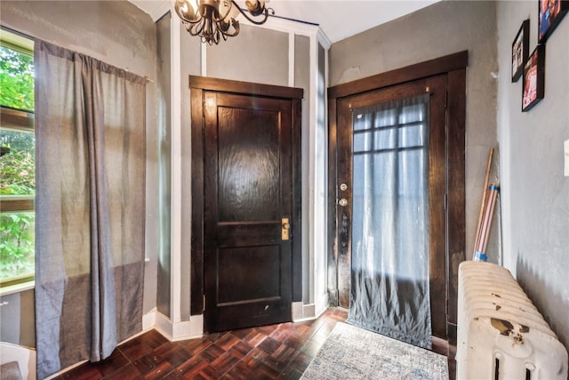 foyer entrance featuring radiator, dark parquet flooring, and an inviting chandelier