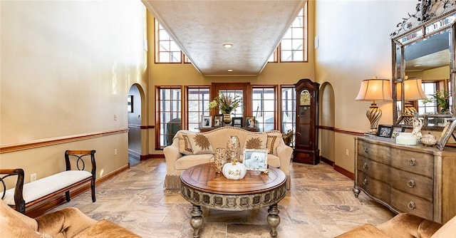 sitting room with a high ceiling, arched walkways, a wealth of natural light, and baseboards