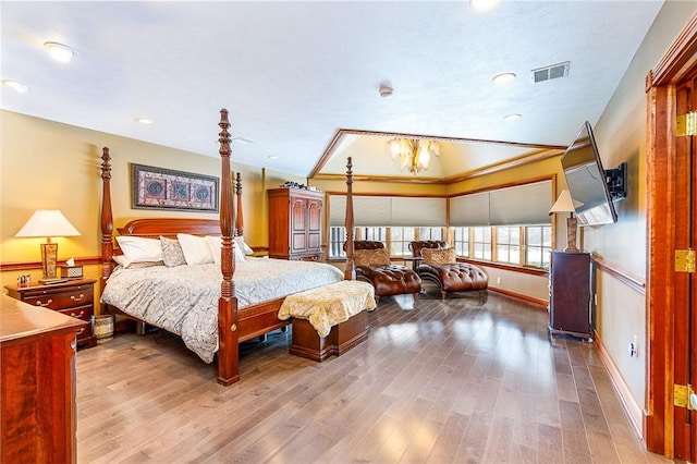bedroom featuring a chandelier, crown molding, visible vents, baseboards, and wood finished floors