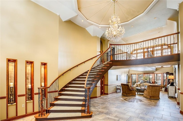 staircase featuring stone finish flooring, baseboards, a notable chandelier, and a high ceiling