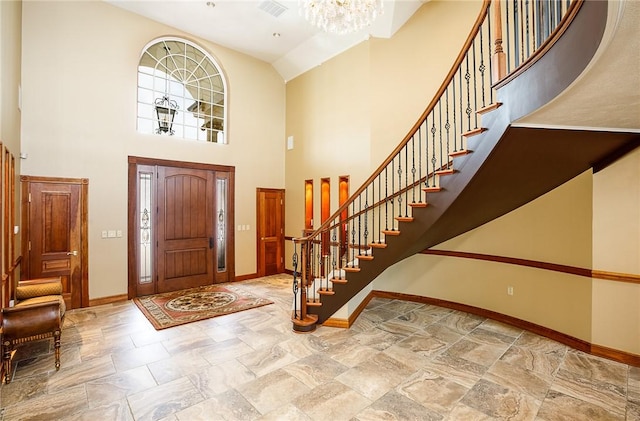 entrance foyer with high vaulted ceiling, stairway, a chandelier, and baseboards