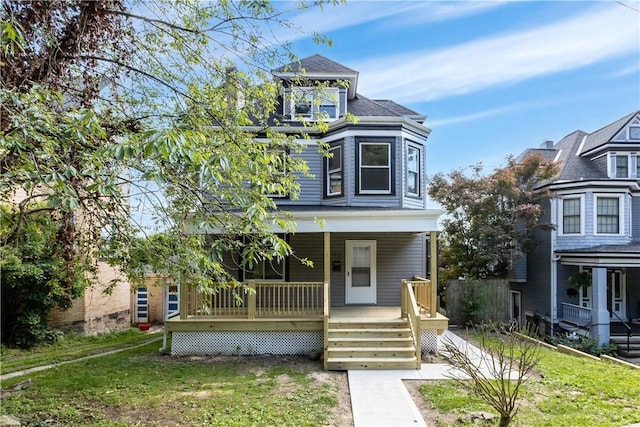 victorian-style house featuring covered porch and a front yard