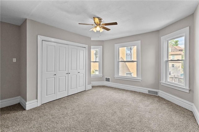 unfurnished bedroom with carpet flooring, multiple windows, ceiling fan, and a closet