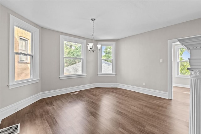 unfurnished dining area featuring plenty of natural light, wood-type flooring, and an inviting chandelier