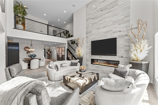 living room with a towering ceiling, tile walls, light wood-type flooring, and a fireplace