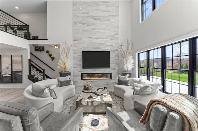 living room with a towering ceiling, a tile fireplace, hardwood / wood-style flooring, and tile walls