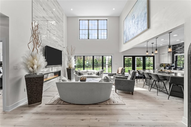 living room with a high ceiling, a premium fireplace, and light hardwood / wood-style flooring