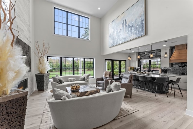 living room with a towering ceiling, a fireplace, and light wood-type flooring