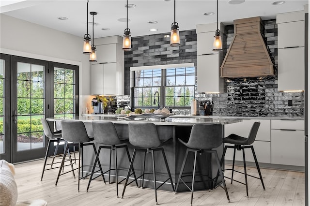 kitchen with custom exhaust hood, plenty of natural light, and light hardwood / wood-style floors