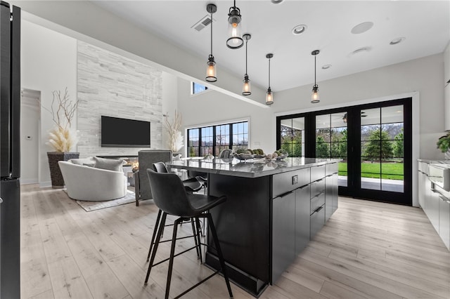 kitchen with decorative light fixtures, a kitchen island, a breakfast bar area, light wood-type flooring, and french doors