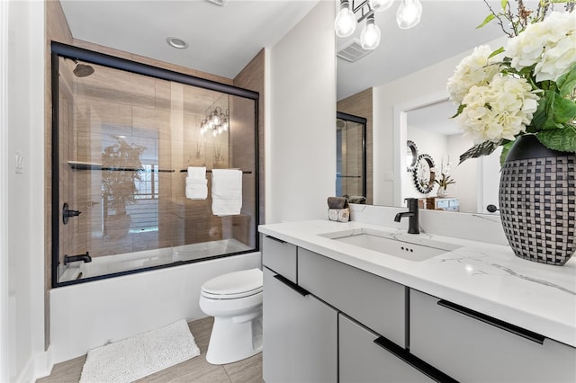 full bathroom with shower / bath combination with glass door, a chandelier, toilet, and large vanity