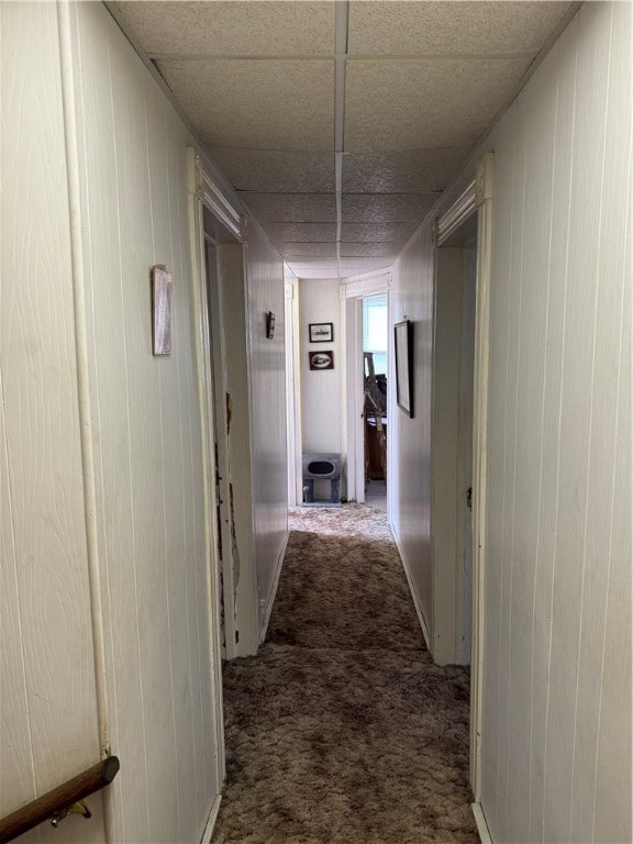 corridor with a paneled ceiling and dark carpet