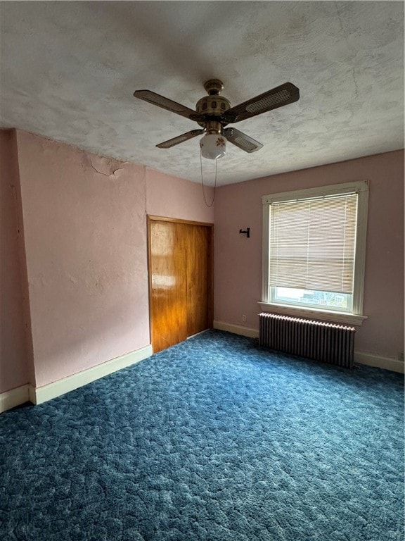 spare room with carpet, radiator heating unit, and ceiling fan