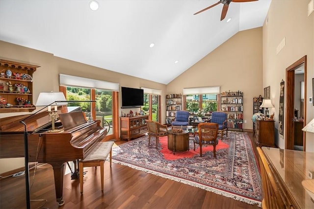 living room with ceiling fan, a healthy amount of sunlight, wood-type flooring, and high vaulted ceiling