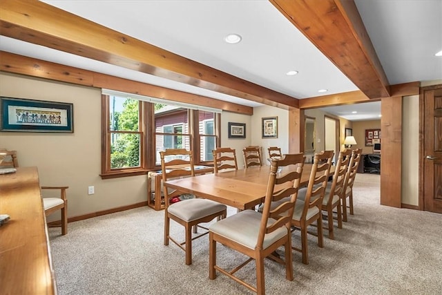 dining room with beam ceiling and light colored carpet