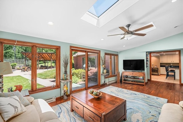 living room featuring hardwood / wood-style flooring, a baseboard radiator, ceiling fan, and vaulted ceiling with skylight