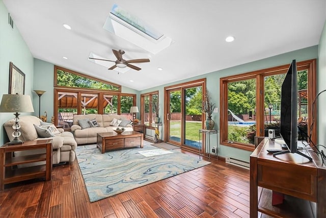 living room with ceiling fan, dark hardwood / wood-style flooring, lofted ceiling with skylight, and baseboard heating