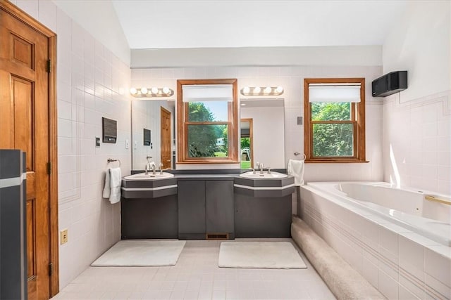 bathroom featuring tile walls, a healthy amount of sunlight, and vaulted ceiling