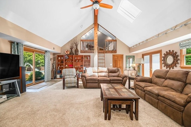 carpeted living room with high vaulted ceiling, french doors, a skylight, ceiling fan, and beam ceiling