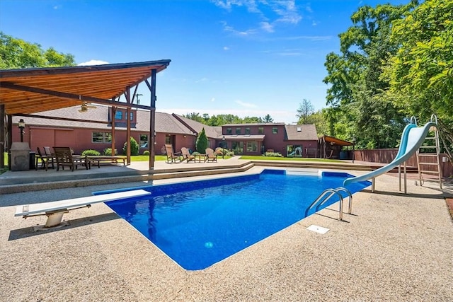 view of pool featuring a diving board, a patio, and a water slide