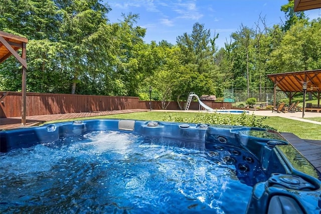 view of pool featuring a yard, a hot tub, and a deck