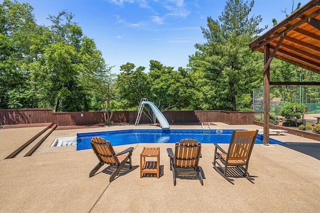 view of swimming pool featuring a patio area, a diving board, and a water slide