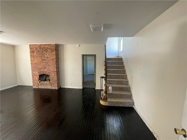 staircase featuring a fireplace, brick wall, and dark hardwood / wood-style flooring