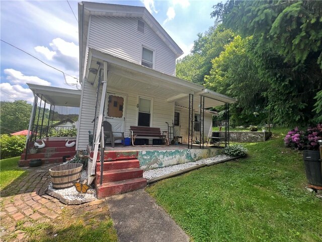 back of house featuring a lawn and a porch