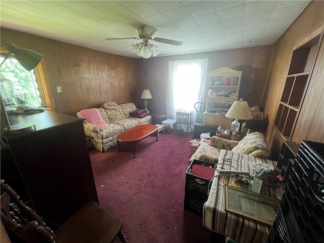 sitting room with ceiling fan, carpet flooring, and wood walls