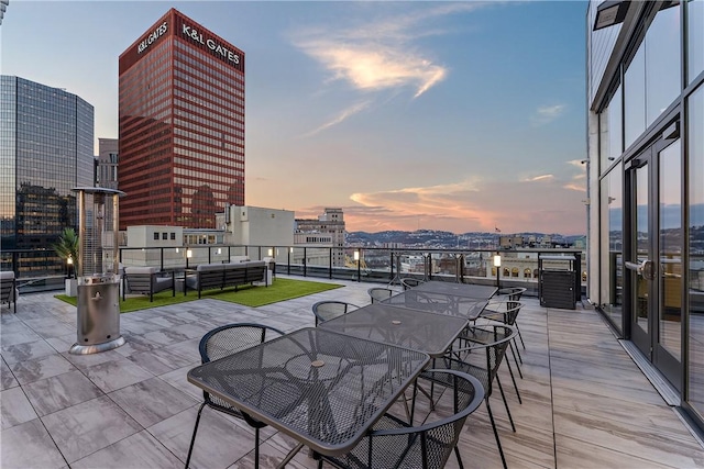 patio terrace at dusk with a view of city, outdoor dining area, and an outdoor hangout area
