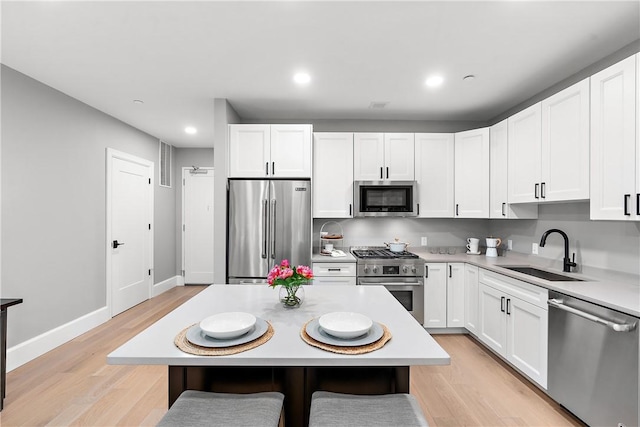 kitchen featuring a sink, light countertops, premium appliances, and light wood finished floors