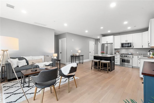 living area featuring visible vents, recessed lighting, light wood-style floors, and baseboards