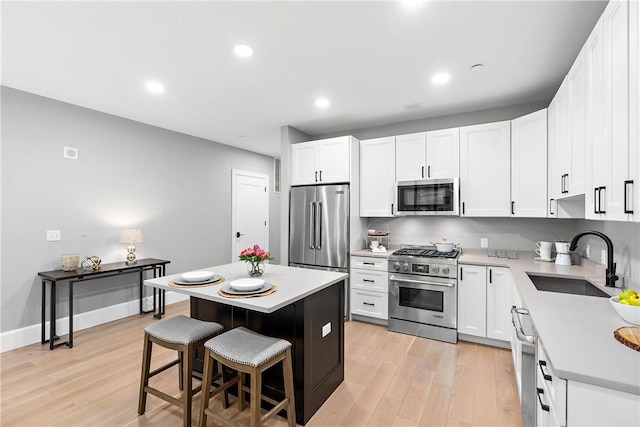 kitchen featuring light wood-type flooring, a sink, a kitchen bar, and premium appliances